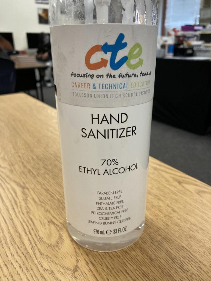 Hand sanitizer bottle sitting on a wooden table in a classroom