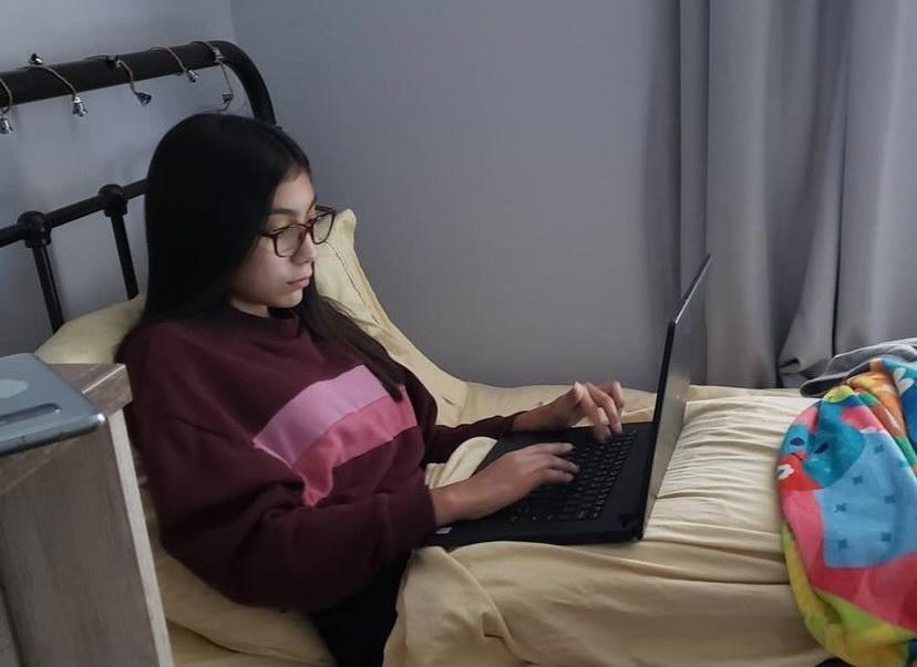 Girl lying on bed with a computer on her lap