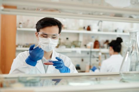 A pharmacist working with blood samples and in the back there is a different pharmacist