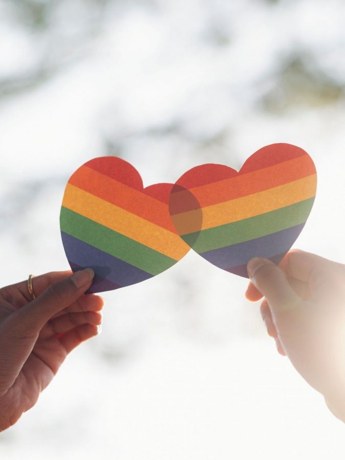 Two Hands holding Rainbow Colored Hearts