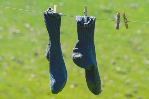 Black socks hanging on a clothes line.