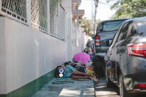 People laying on pavement next to parked cars